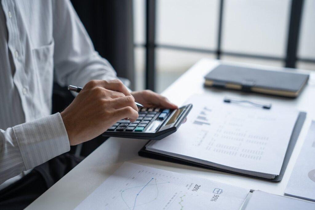 A suited man using a calculator to help with wealth management.